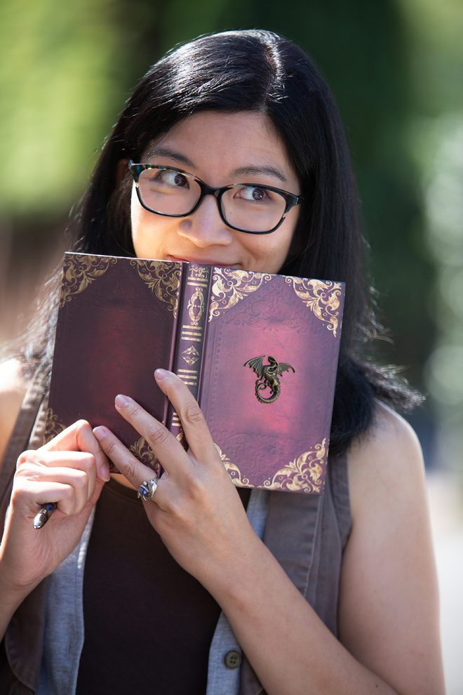 Photo of Eliza Chan holding an open book over her mouth